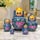 Hand-painted blue Russian matryoshka nesting dolls set of 5 displayed on a polished marble table in a modern home interior. Traditional wooden nesting dolls with pink floral artwork, green leaves, glossy finish, and blonde faces, photographed as elegant folk art home décor.