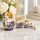 Hand-painted white Russian matryoshka nesting dolls set of 5 displayed on a polished marble table in a modern home interior. Traditional wooden nesting dolls with blue floral artwork, gold accents, glossy finish, and blonde faces, photographed as elegant folk art home décor.