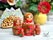Red hand-painted Russian nesting dolls with strawberry design displayed in a cozy home interior with fresh flowers.