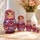 Hand-painted pearlescent raspberry pink Matryoshka dolls with daisy flowers displayed in a cozy home interior.