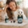Panda matryoshka nesting dolls displayed on a fringed white tablecloth, with five Russian wooden dolls arranged in different sizes. A young girl admires the handmade set in a bright, cozy home interior