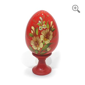 Œuf de Pâques rouge peint à la main avec motif floral en style russe Zhostovo, bois laqué brillant avec décor doré, présenté sur support et fond blanc épuré