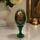 Smolensk Mother of God icon displayed on a green decorative wooden Easter egg showcased in a refined home interior with soft ambient lighting.